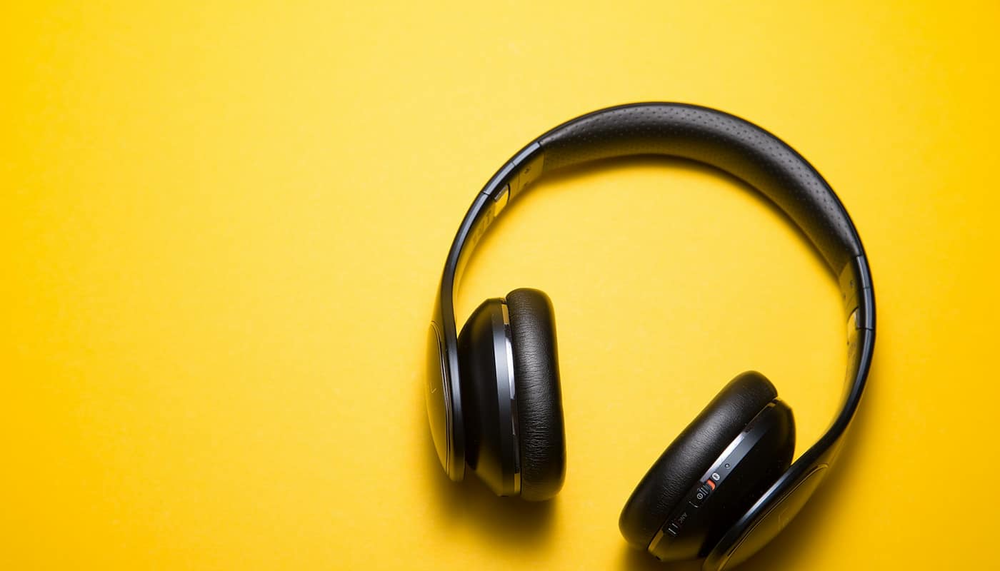 Black wireless headphones on a yellow background