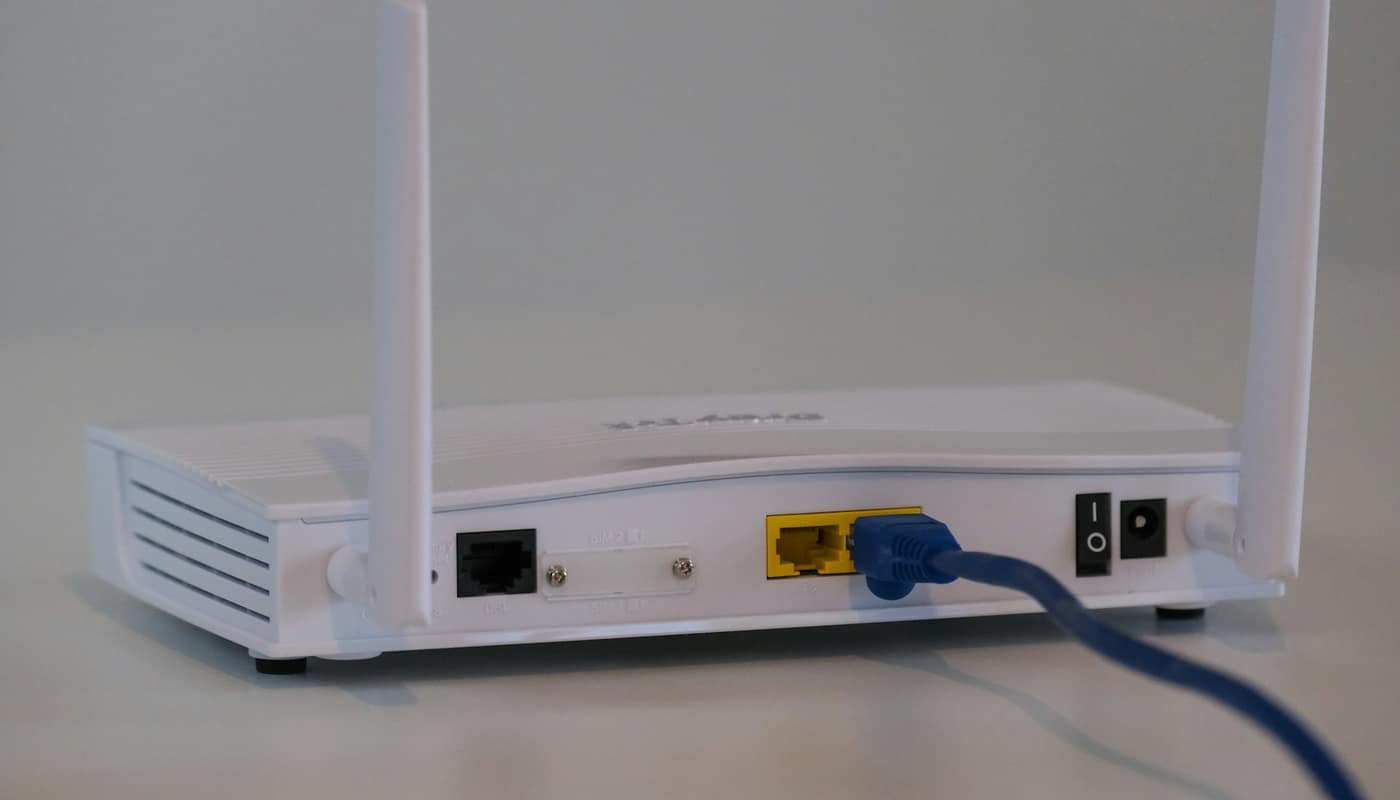 A white broadband router with a blue network cable