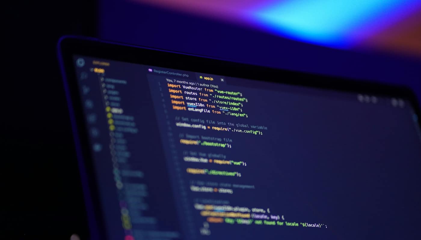 Code on a laptop screen seen at an angle, with blue and purple light