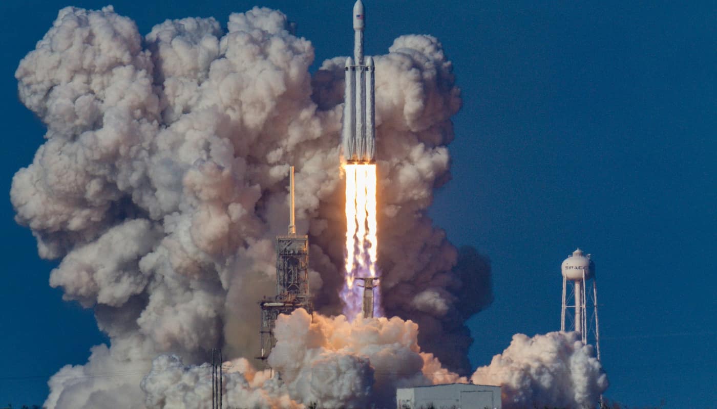 A rocket lifting off in a large cloud of smoke and steam