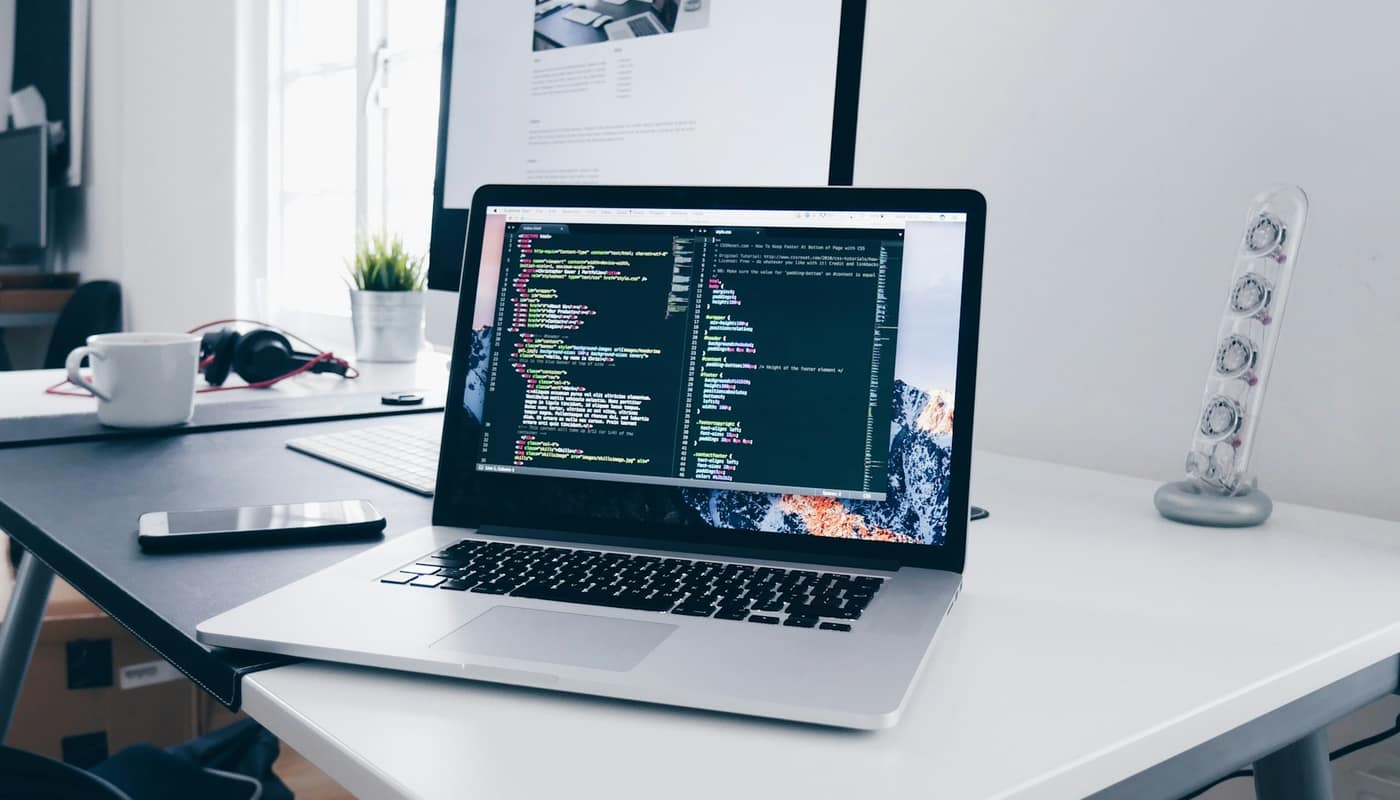 A laptop showing code on a white desk