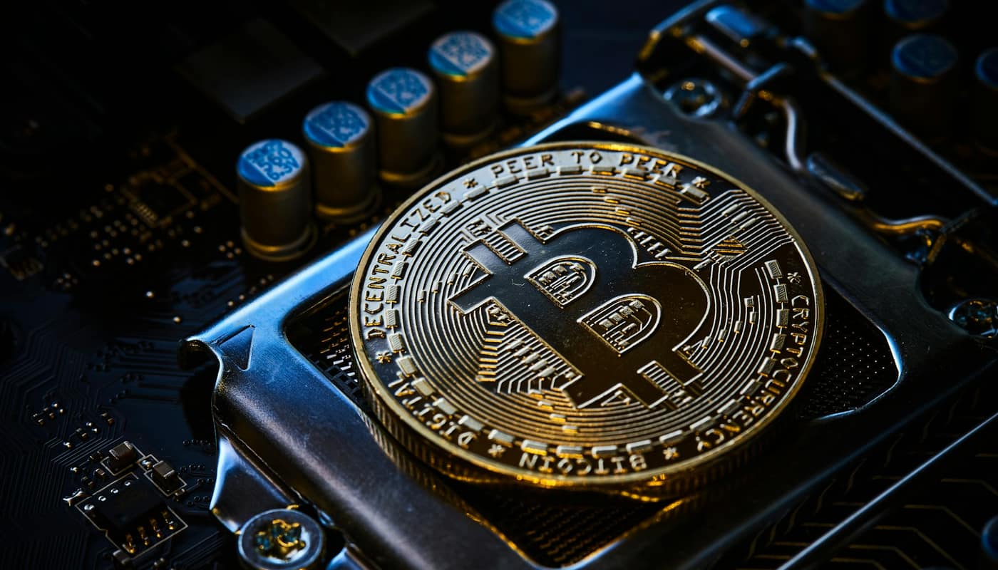A gold bitcoin coin sitting on a computer motherboard